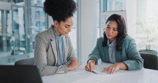 two women signing papers