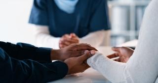 couple holding hands in front of doctor 