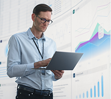 man with laptop and charts in background