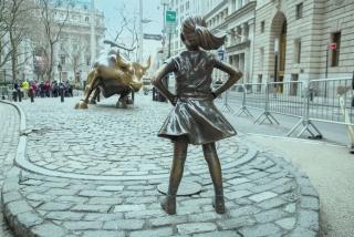 Fearless girl statue facing the Wall St. bull statue stock photo used by Woodruff Sawyer.