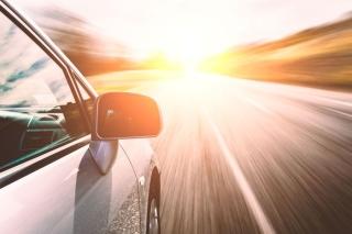 Car driving down road as sun shines