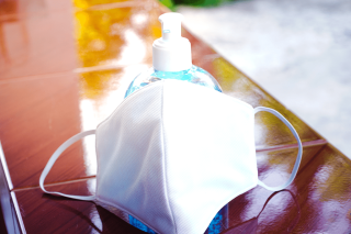 image of a fabric mask sitting next to a bottle of hand sanitizer