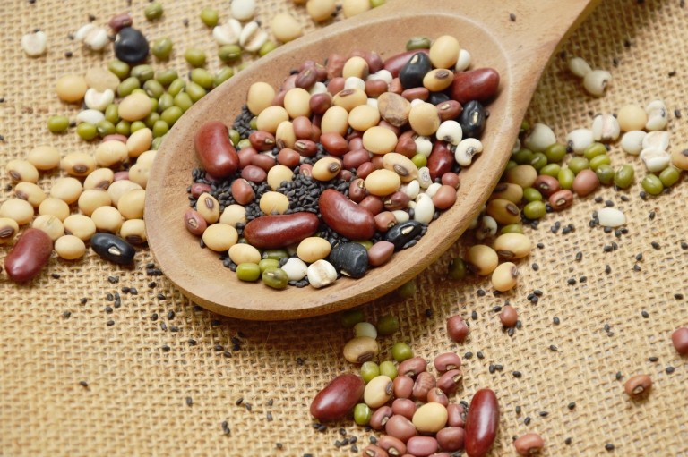 beans and lentils in wooden spoon on sack