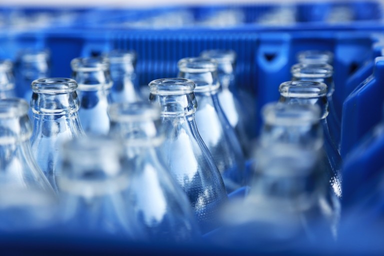 A blue plastic crate filled with empty bottles