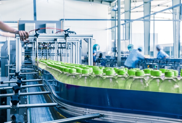 Worker on production line with green bottles in factory