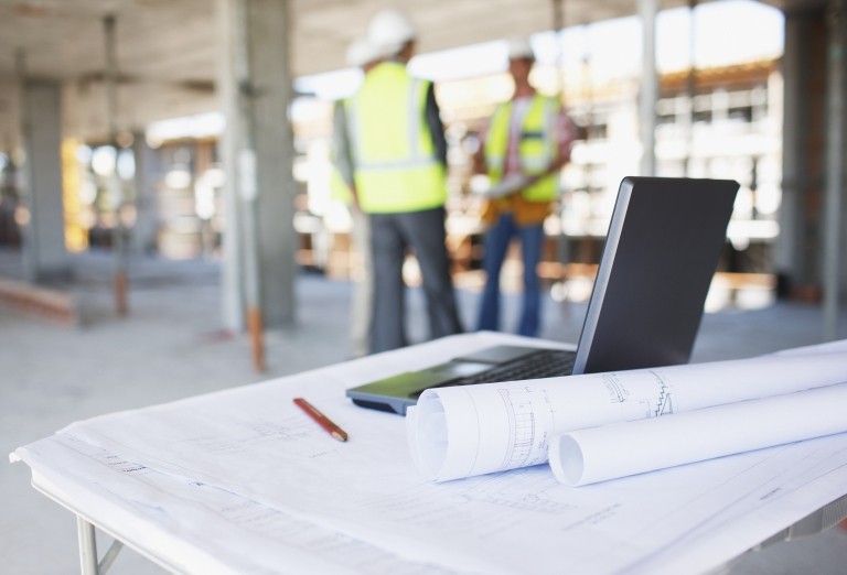 Construction contract on table with construction workers in background