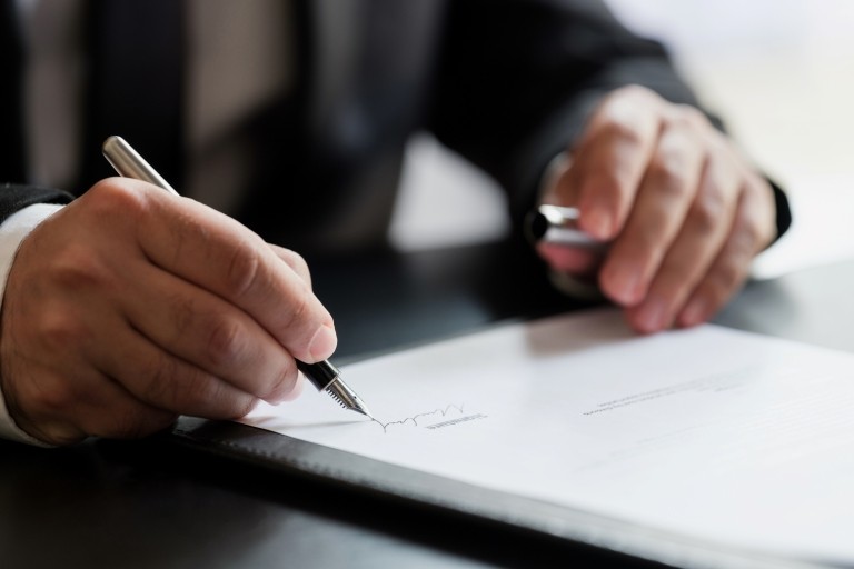 Businessman in suit signing paperwork