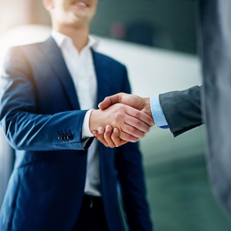 Two professionals shaking hands in an office, symbolizing a successful business deal