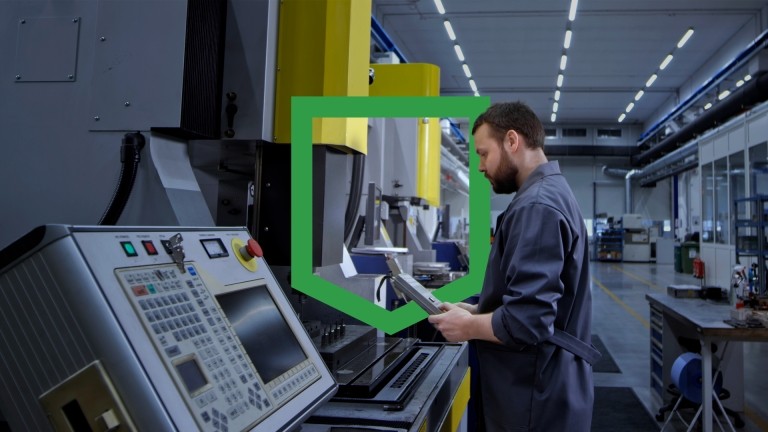 A man in a factory observing a machine in operation