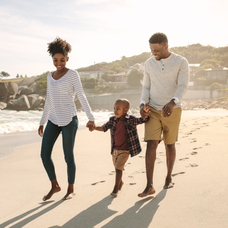 family enjoying a beach stroll with their son