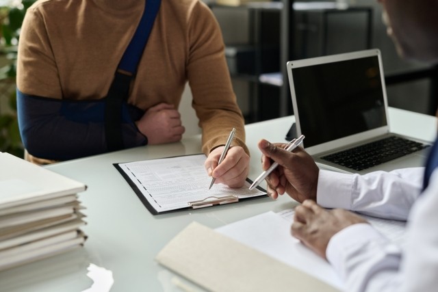 injured man signing forms with claims professional