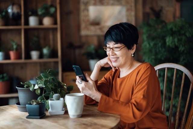 Smiling senior woman managing online banking with mobile app on smartphone