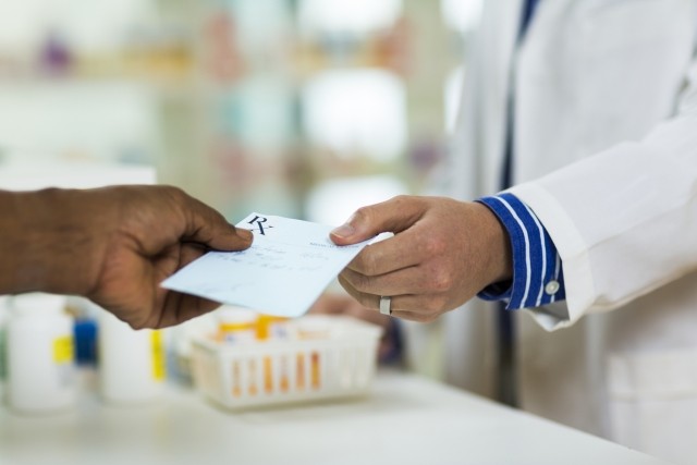 A man handing a prescription to a pharmacist