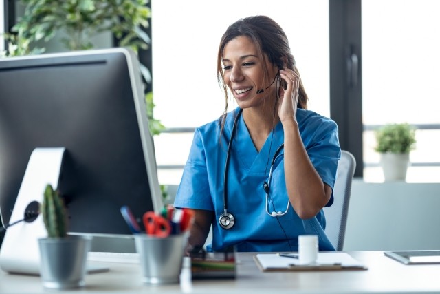 Female doctor talking with earphone while explaining medical treatment to patient through a video call