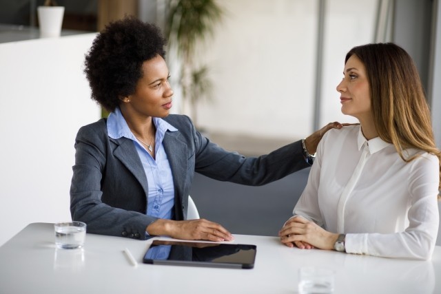 adult businesswoman comforting her colleague in a modern office