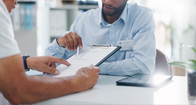 Man, doctor and hands with form in consultation for signature