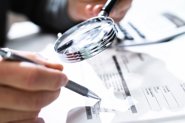 Person checking accounting numbers with a magnifying glass