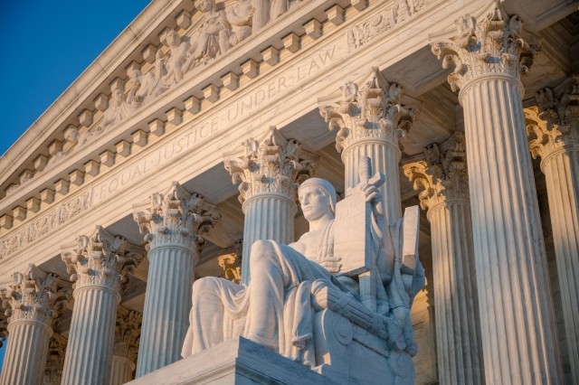 Sunset glow illuminated statue and colonnade of US Supreme court in Washington DC, USA