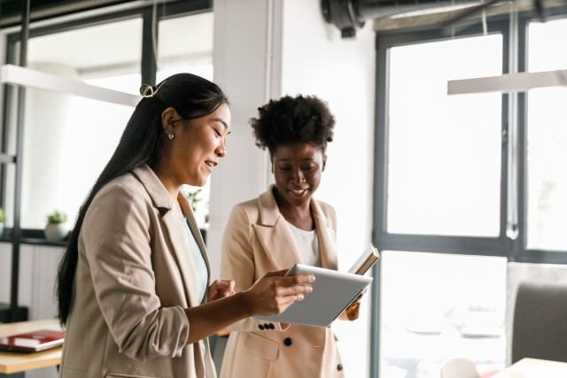 two women looking at a tablet in an office