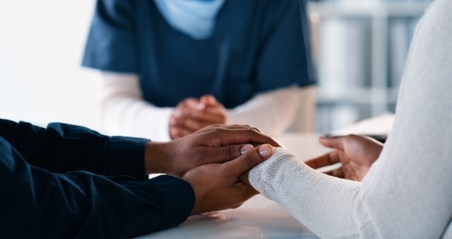 couple holding hands in front of doctor