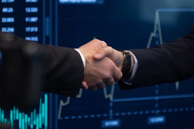 Two friendly men working in office, shaking hands after made right financial forecast and successful sales