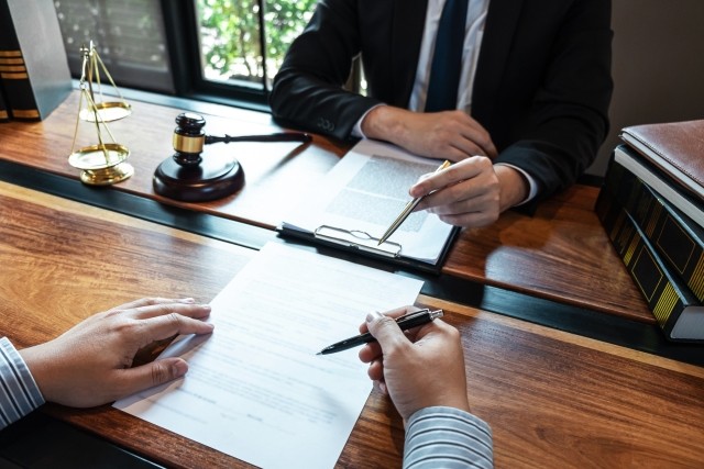 Professional male lawyer or counselor discussing negotiation legal case with client meeting with document contract in office