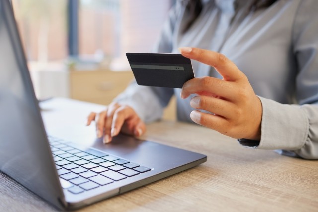 person looking at credit card in front of laptop