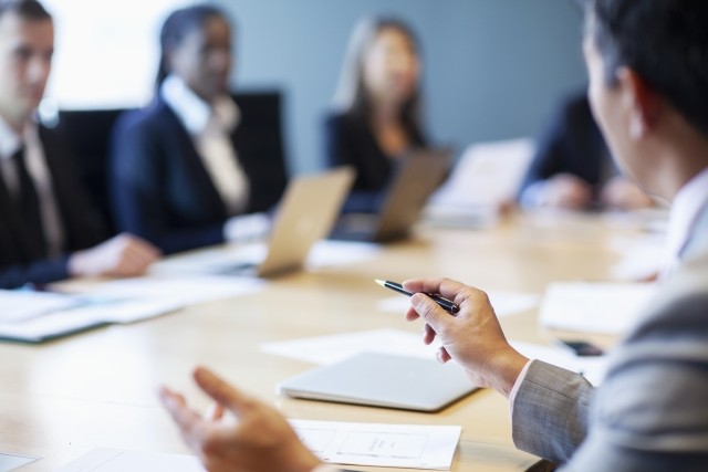 Hands of businessman gesturing ideas decisions with pen pointing leadership to work colleagues in business meeting at board room conference table