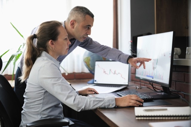 Businesspeople working in the office on stock market exchange data using desktop computer