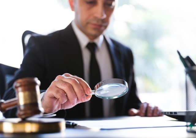 Man In Black Suit Reading A Legal Document Carefully Using Magnifying Glass