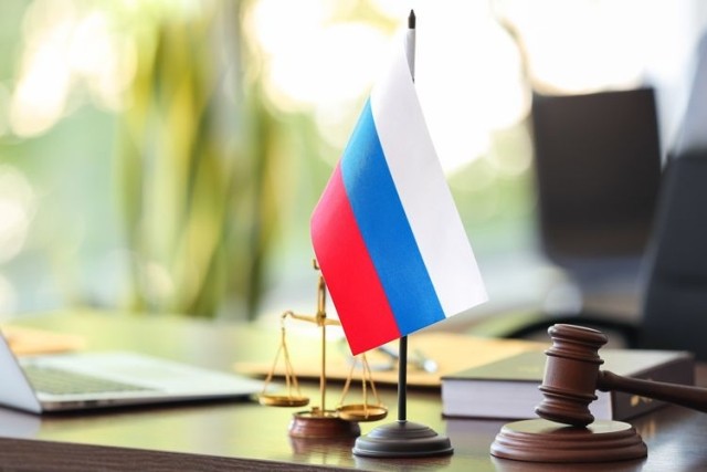 Judge gavel, scales and Russian flag on table in office