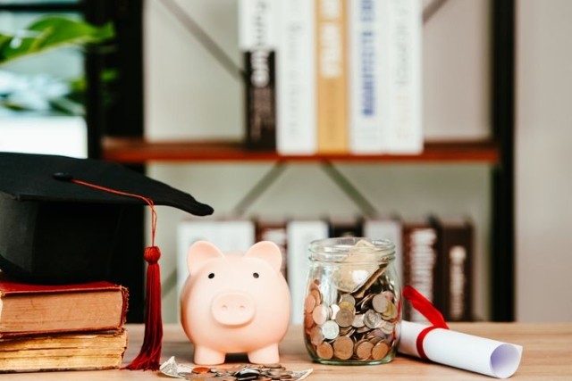 Student Loan Savings in Piggy Bank with diploma and graduation cap.