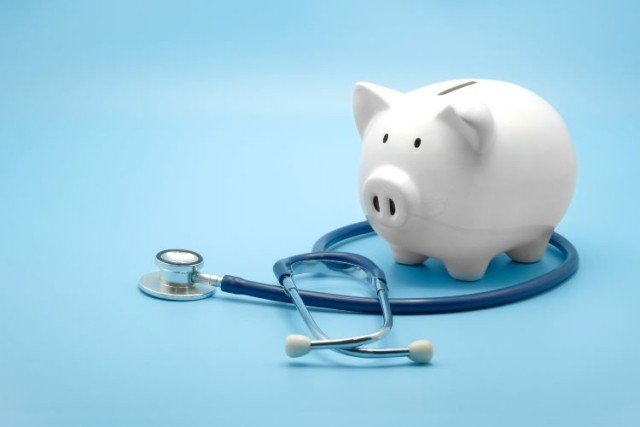 Piggy bank with stethoscope isolated on light blue background with copy space