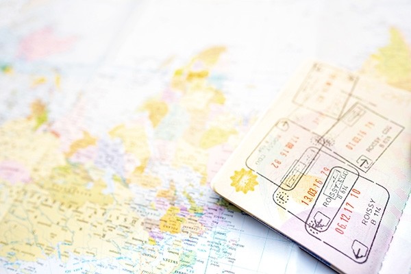 Image of an open passport with customs stamps lying on top of a world map