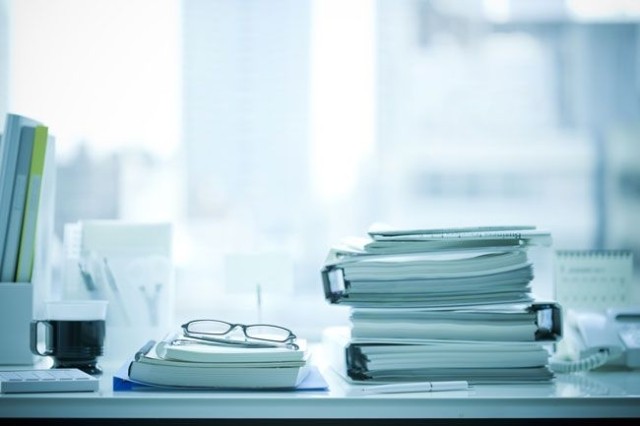 Stack of binders and administrative paperwork on desk