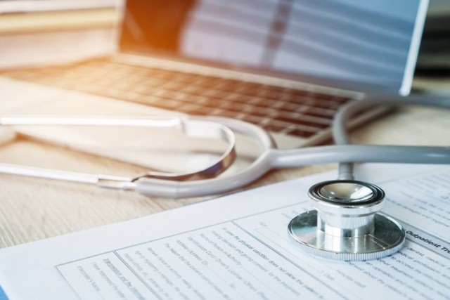 Stethoscope on medical paperwork and laptop