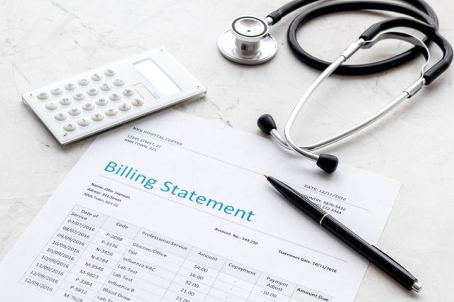 Medical billing statement with a pen, calculator and stethoscope