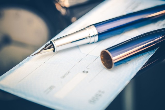 Blank check with a fountain pen lying on it stock photo used by Woodruff Sawyer.