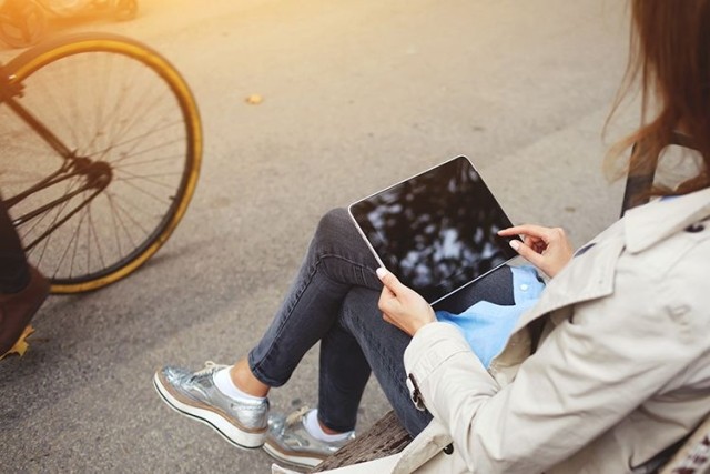 Woman sitting on park bench using tablet device