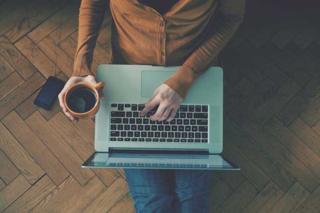 Woman using laptop while sitting on floor