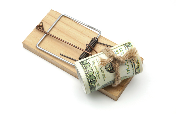 An image of a roll of  green dollar bills tied up in a knot attached to a rat trap.