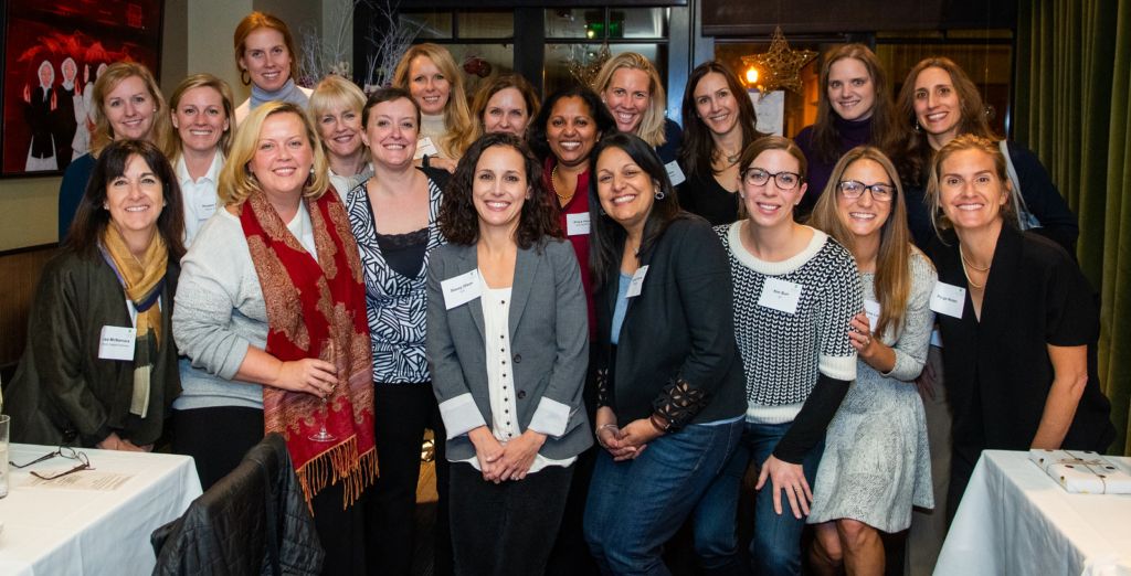 An image of women smiling in a conference room for the Executive Women Network Event 2018.