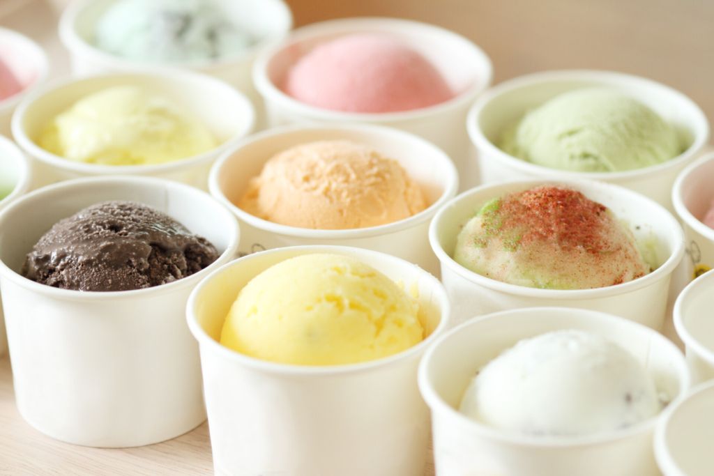 Image of various flavors of ice cream in paper cups.