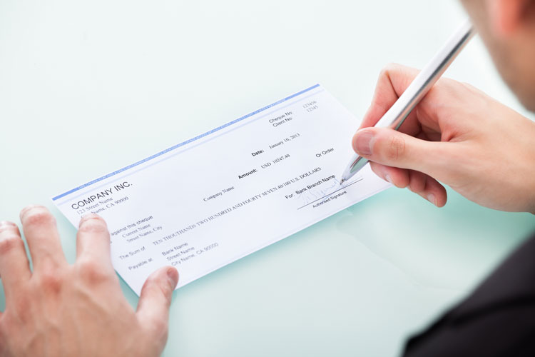 Person writing a check stock image used by Woodruff Sawyer.