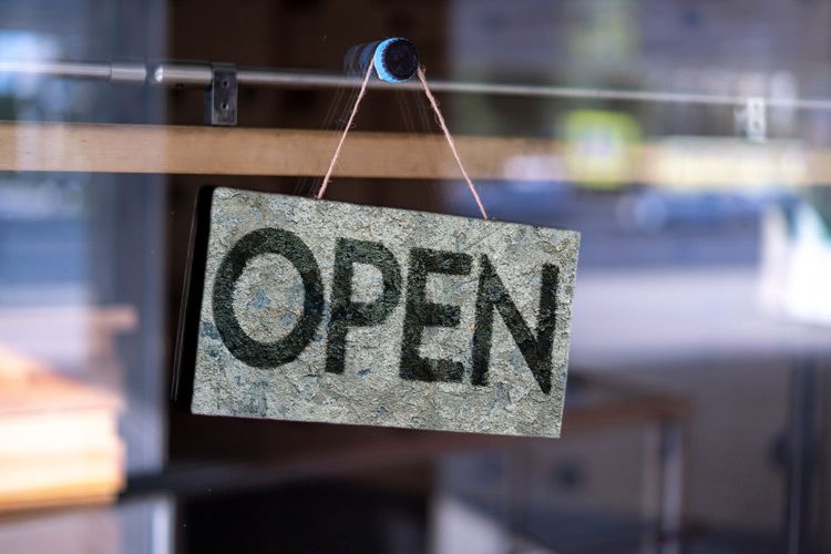 Open sign hanging on glass window of a business storefront
