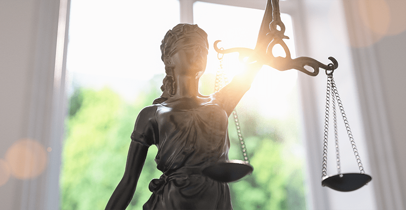 Statue of Justice in front of a brightly lit window